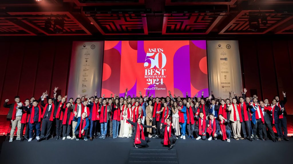 A large group of people posing in front of a backdrop at Asia’s 50 Best Restaurants.