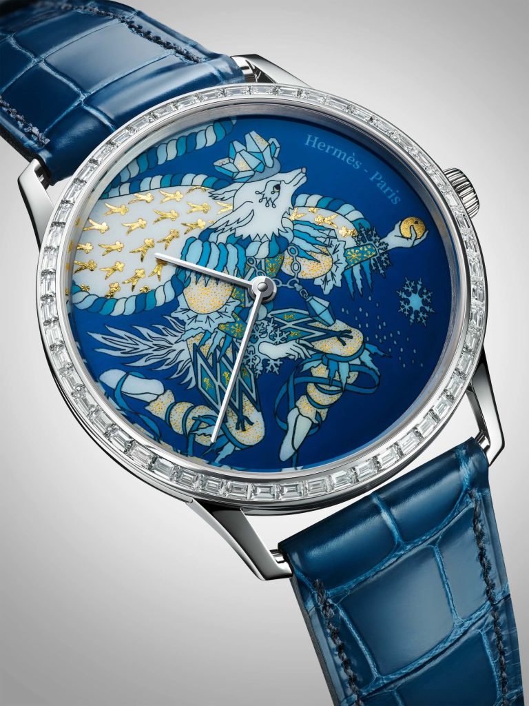 Blue Hermès watch with a winter theme showing a wolf rendered in enamel and gold flakes. 